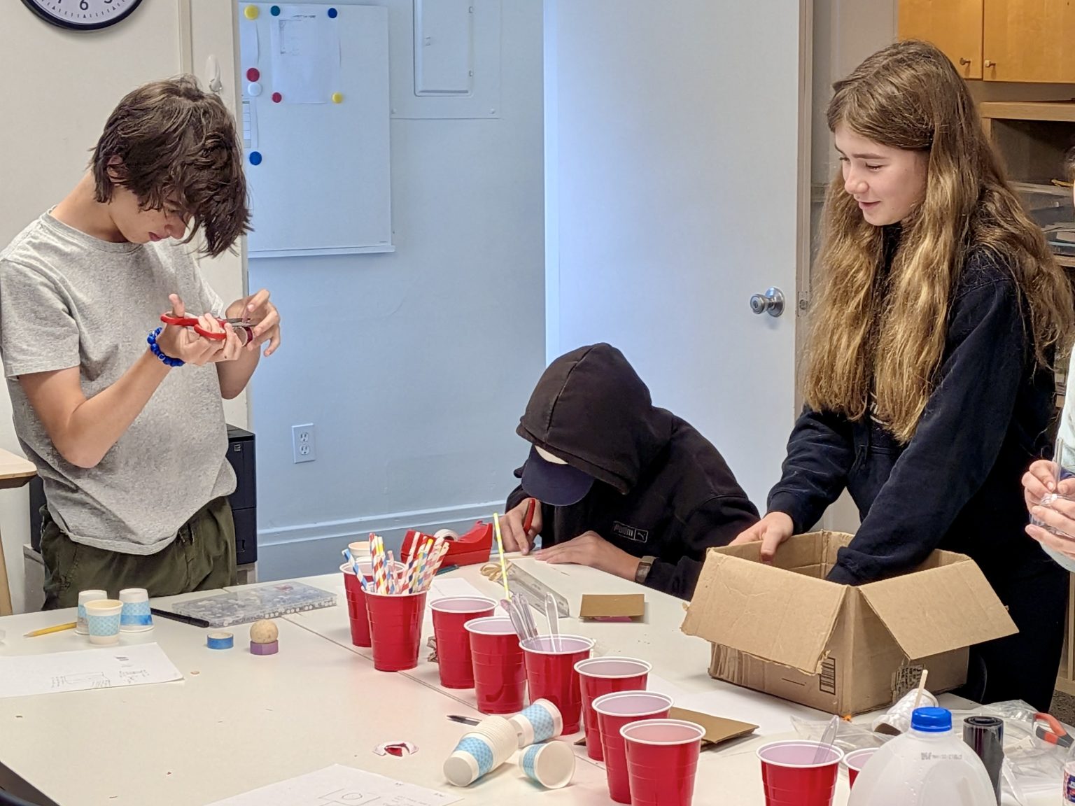 Students running a science experiment with cups and materials