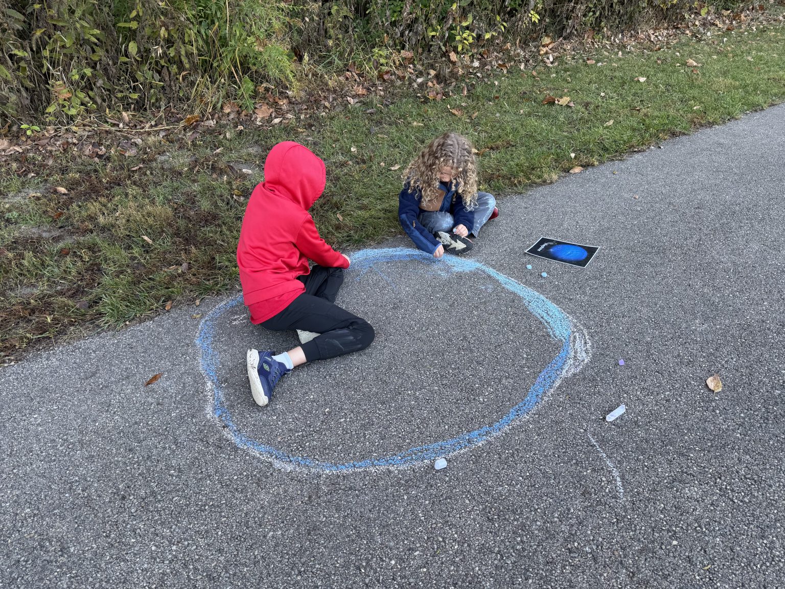 Young children playing outdoors with sidewalk chalk