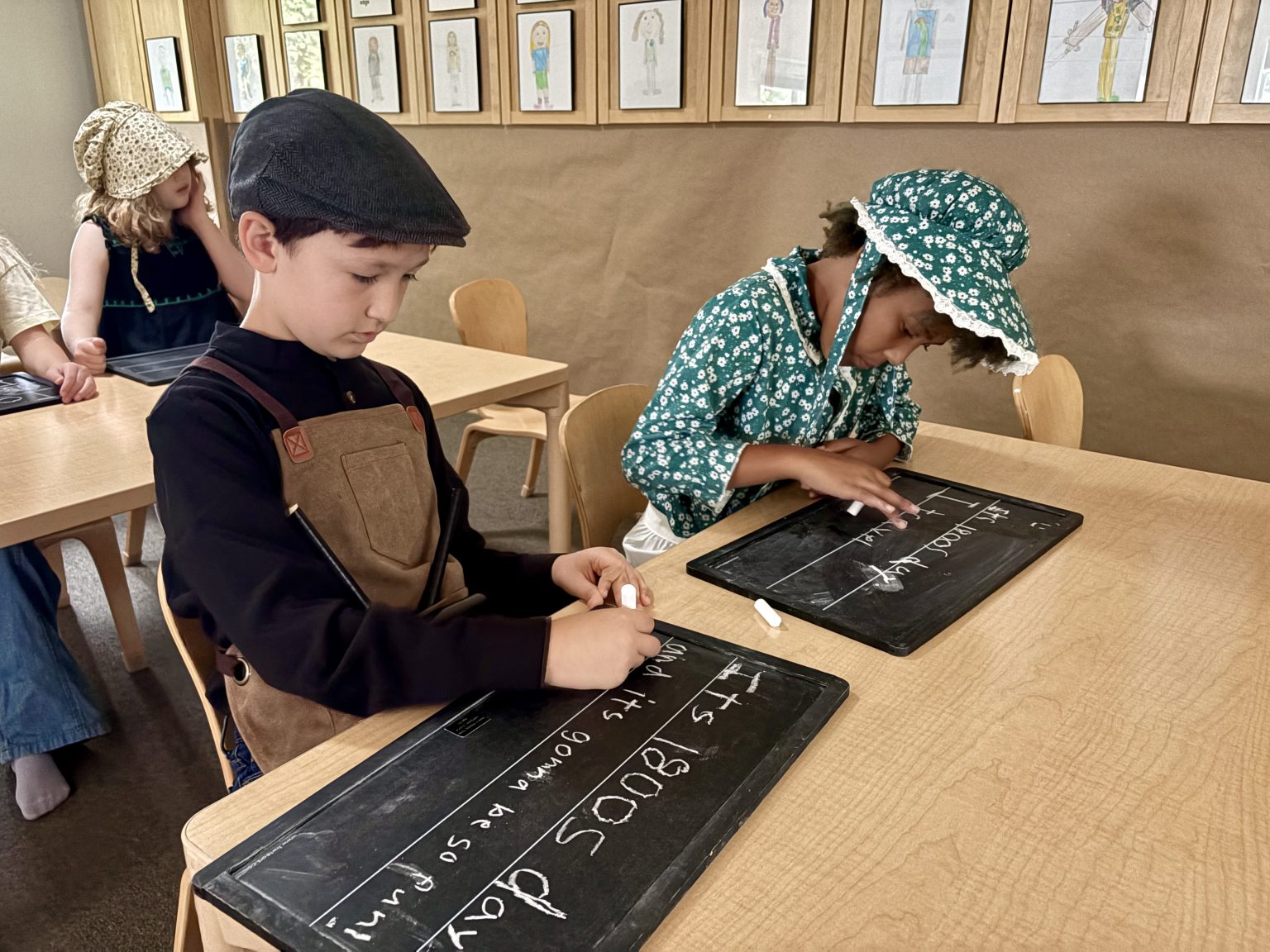 Students writing on slate boards during a hands-on lesson